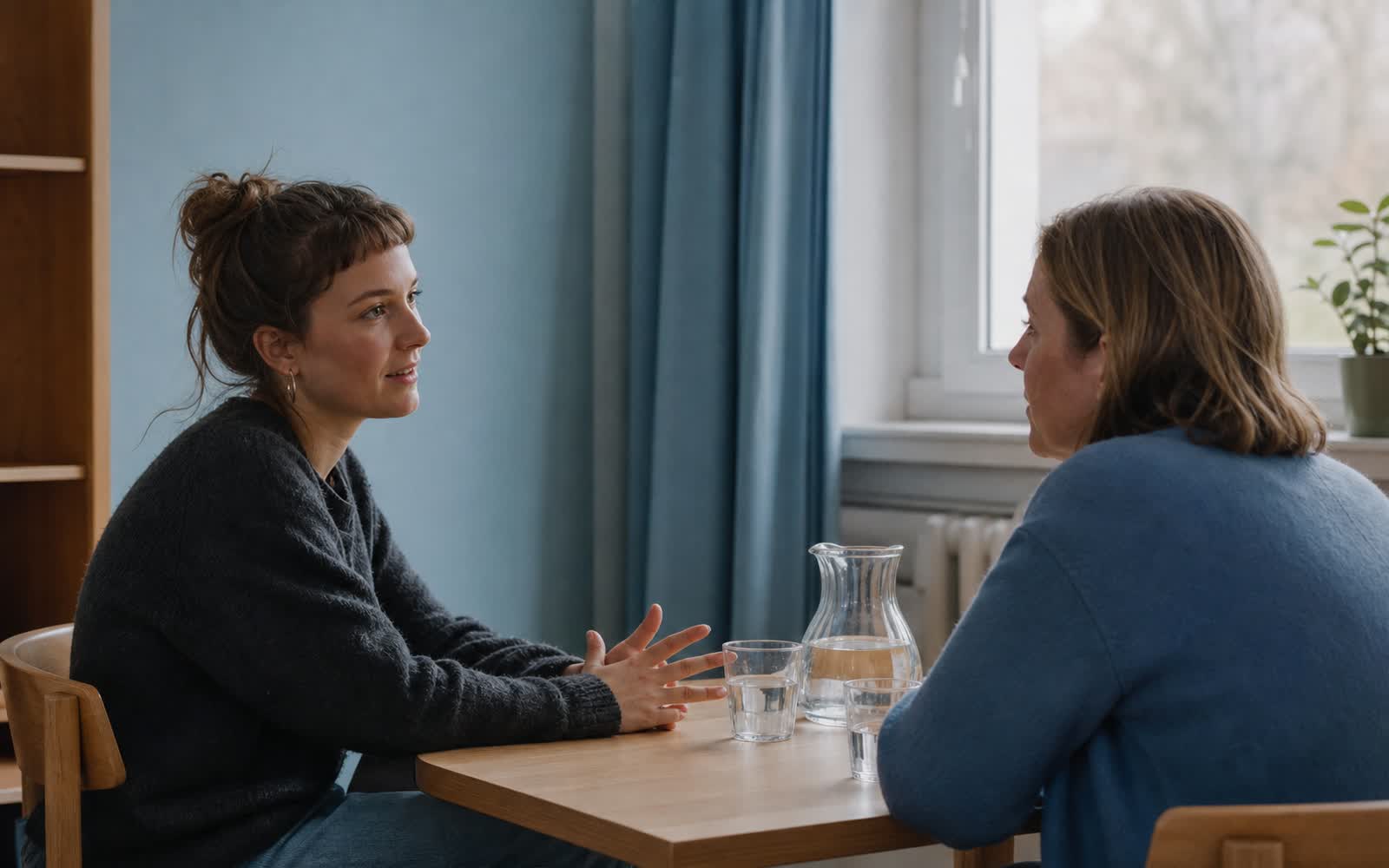 Symbolbild: Zwei Personen im Gespräch über Eck, eine hört aufmerksam zu, offene Körperhaltung, Gesichter im Halbprofil